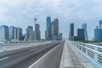 Fototapeta na wymiar road through the bridge with city skyline background