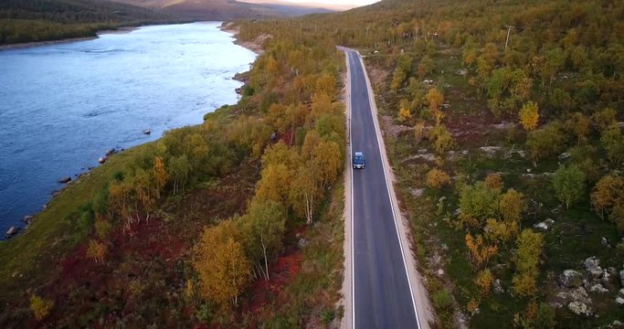 Autumn color road, Cinema 4k aerial view of a car driving on road 970 the tenontie, near tenojoki river, at the border of norway and utsjoki, on a sunny evening dawn, in Lapland, Finland