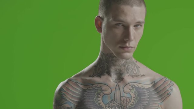 Handsome sexy young man stylish with tattoo on his neck, torso and hand - middle shot portrait studio - greenscreen Prores - cinematic lighting