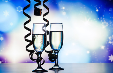 two champagne glasses with ribbons against holiday lights and fireworks - New Year celebrations