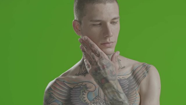 Handsome sexy young man stylish with tattoo on his neck, torso and hand - middle shot portrait studio - greenscreen Prores - cinematic lighting