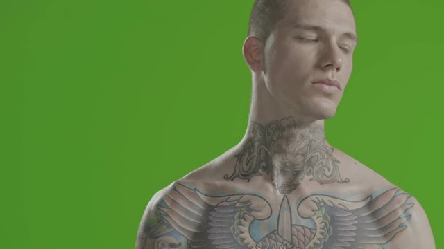Handsome sexy young man stylish with tattoo on his neck, torso and hand - middle shot portrait studio - greenscreen Prores - cinematic lighting