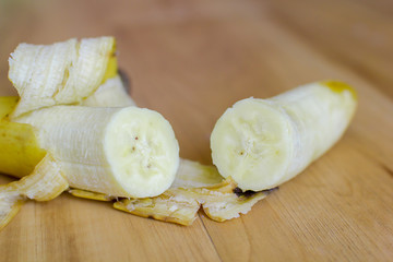 Banana with banana peel on wooden floor.