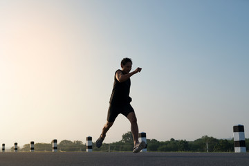 Fototapeta na wymiar Asia young man running in the time during sunrise on dam road exercise.Healthy lifestyle