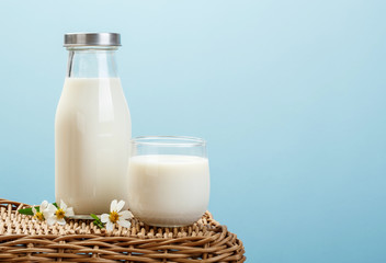 A bottle of rustic milk and glass of milk on wicker on a blue background, tasty, nutritious and healthy dairy products