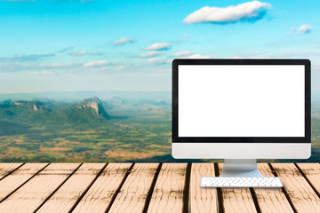 Modern computer blank monitor screen on wooden table with view point of the mountain landscape blurred background