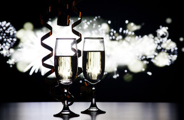 two champagne glasses with ribbons against holiday lights and fireworks - New Year celebrations