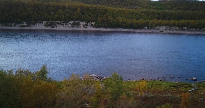 Autumn river, Cinema 4k aerial tilt view of tenojoki river at the border between norway and utsjoki town, on a sunny autumn evening dawn, in utsjoki, Lapland, Lappi, Finland