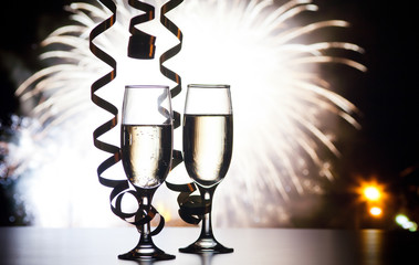 two champagne glasses with ribbons against holiday lights and fireworks - New Year celebrations