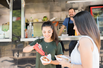 Women eating hot dogs from food truck