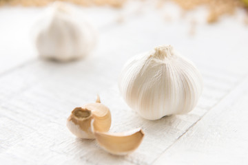 Beautiful garlic bulbs and some cloves on white wood table