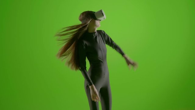 Attractive girl young fashion model wearing a VR headset shot in green screen studio . Interactive futuristic gesture . Medium s