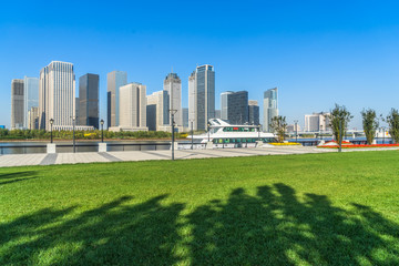 cityscape and skyline of Tianjin from meadow at sunny day