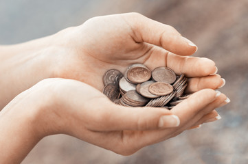 Handful of coins in palm female hands. Concept of saving and passive income. Instagram beige toned