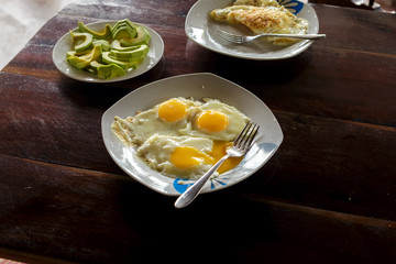 Breakfast table with plate fried eggs, scrambled eggs and avocado