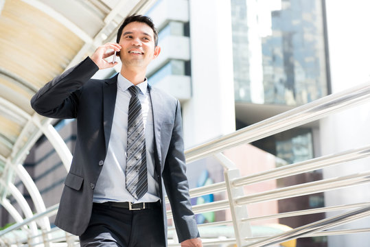 Enthusiastic Asian business man takling on mobile phone
