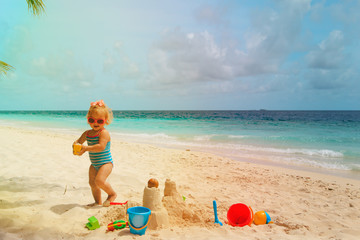 cute little girl play with sand, building castle on beach