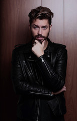 Obraz premium Portrait of young handsome fashionable man against wooden wall.