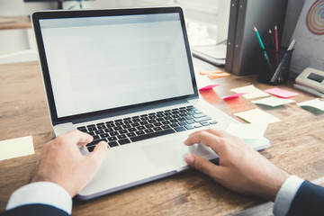 Hands of businessman using notebook computer at working desk in the office