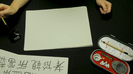 Woman's hand writing chinese calligraphy. Female hand holding a writing brush Chinese characters
