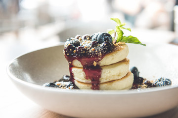 Beautiful appetizing stack of fluffy pancakes topped with fresh blueberries, syrup and ground biscuit