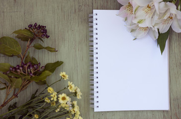 Mockup with blank notepad. Blank sheet. A place for the presentation. Wild flowers on green painted wooden background.