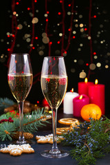 Champagne glasses in holiday setting. Christmas and New Year celebration with champagne. Christmas holiday decorated table with white sparkling wine, vertical