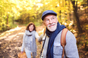 Senior couple on a walk in autumn forest.
