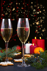 Champagne glasses in holiday setting. Christmas and New Year celebration with champagne. Christmas holiday decorated table with white sparkling wine, vertical