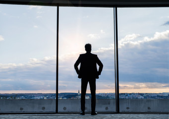 Mature businessman standing at the window in a hotel.