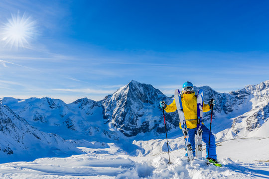 Mountaineer backcountry ski resting along a snowy ridge with skis in the backpack. In background blue sky and shiny sun and Ortler in South Tirol, Italy.  Adventure winter extreme sport.