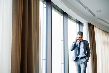Mature businessman with smartphone in a hotel.
