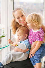 Smiling Caucasian mom holding two children (boy and girl). The concept of a happy family