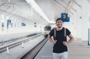 Young traveler walking with backpack on train staition and waiting train