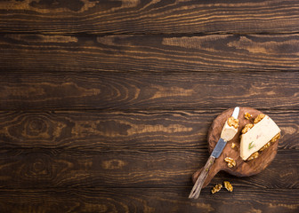 Walnut cheese with cheese and special knife on old wooden round board. Healthy food concept with copy space.