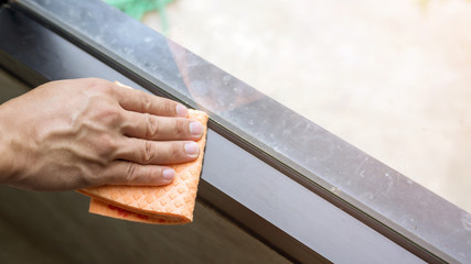 Man use a fabric for cleaning a window.