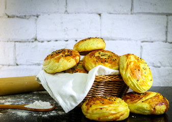 Fresh homemade buns on basket with rustic white brick background.