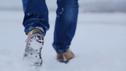 Man walking in snow. Man walking on snow, footprints in snow, behind. Man walks in the winter in the field