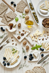 Brie cheese and camembert with nuts and grapes on a white wooden background. View from above
