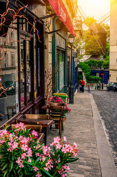 Cozy street with tables of cafe and old mill in quarter Montmartre in Paris, France