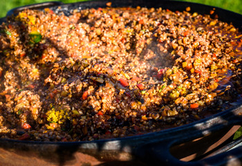 Cooking and making traditional Spanish Paella in iron cast pan.
