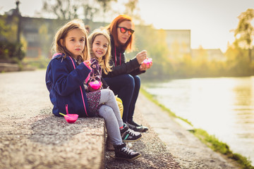 Family eating ice cream, sitting on banks of river Ljubljanica.