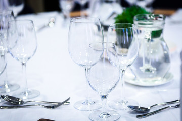 Transparent glasses on a banquet table with spoons and forks.