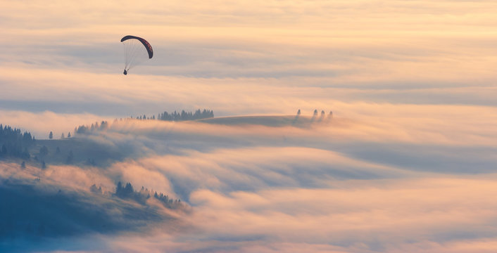 Paraglider over the dense morning fog