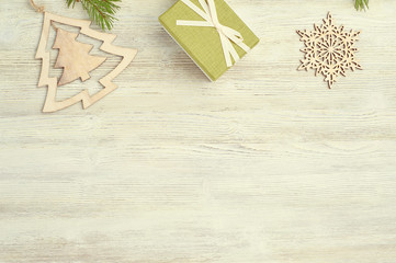 Christmas  background. Wooden toys in the shape of Christmas trees and snowflakes, green gift boxes, natural fir branches on a light wooden background