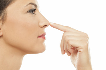 Young woman touching her nose with her finger - obrazy, fototapety, plakaty