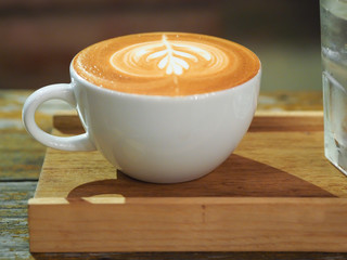 Art latte is on wooden saucer. 