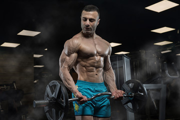 Fototapeta na wymiar Muscular athletic bodybuilder fitness model posing after exercises in gym