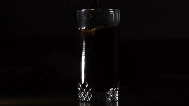 Cola Carbonated Drink Pouring In Glass In Dark  