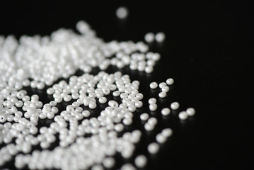 White seed beads scattered on a dark background